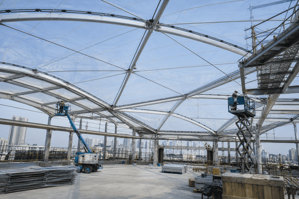 Construction crew installing ETFE cushion modules on a office building roof grid
