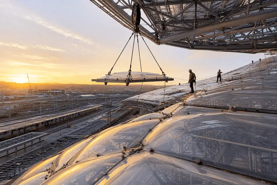 Construction crew installing ETFE cushion modules on a railway station roof grid — Railway Station ETFE Roofing systems