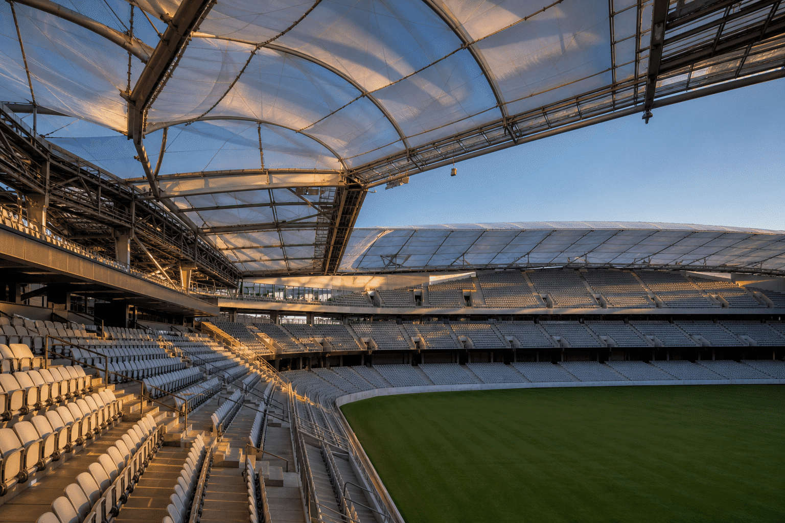 Sweeping translucent ETFE stadium roof geometry over an empty arena bowl at dusk