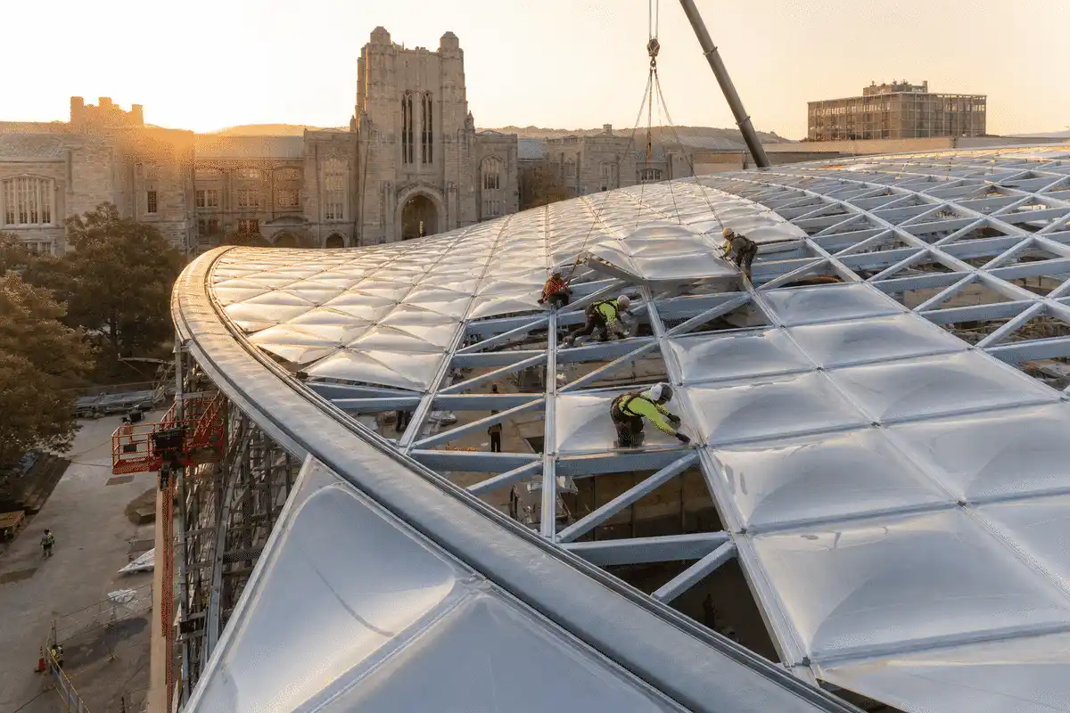 Construction crew installing ETFE cushion modules on a university roof grid — University ETFE Roofing systems