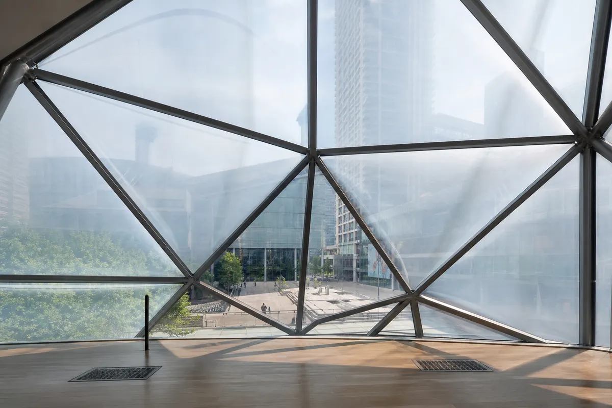Daylit commercial lobby behind a transparent ETFE façade envelope