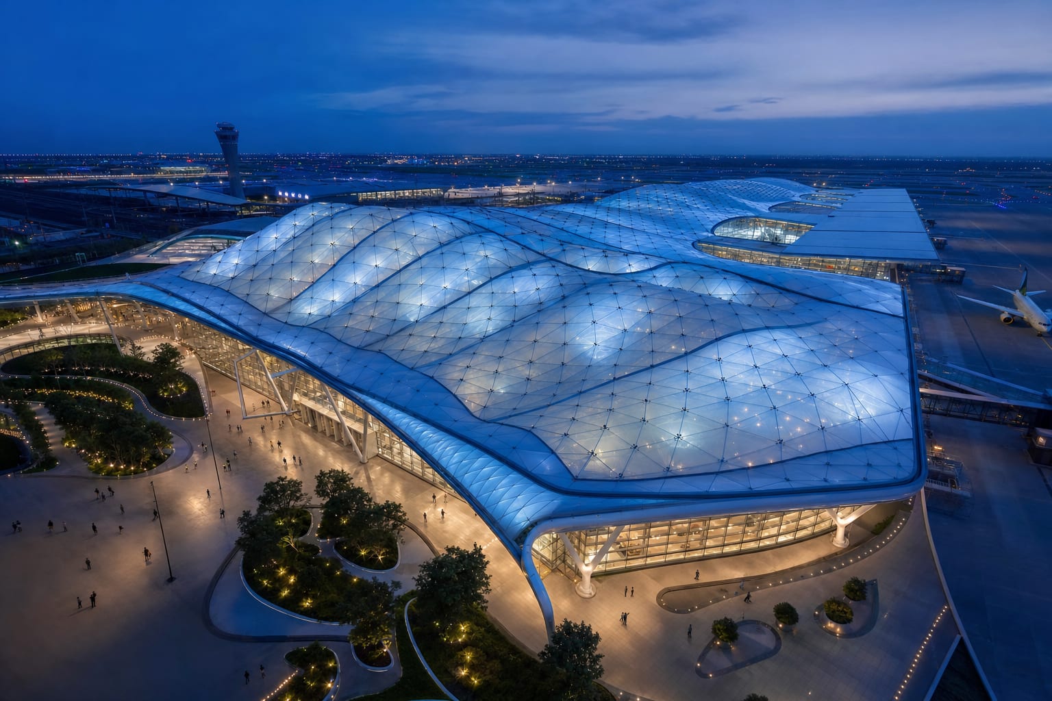 Aerial blue-hour view of an ETFE air cushion roof over an international airport terminal