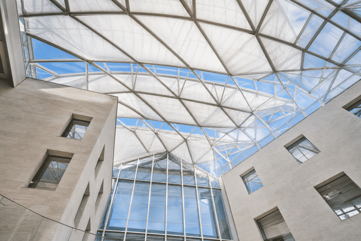 Interior view under luminous ETFE atrium with blue sky beyond
